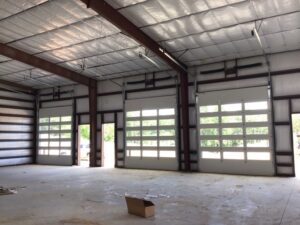 Multiple white glass-paneled commercial garage doors installed in a large building by Magic City Door in Birmingham, AL.