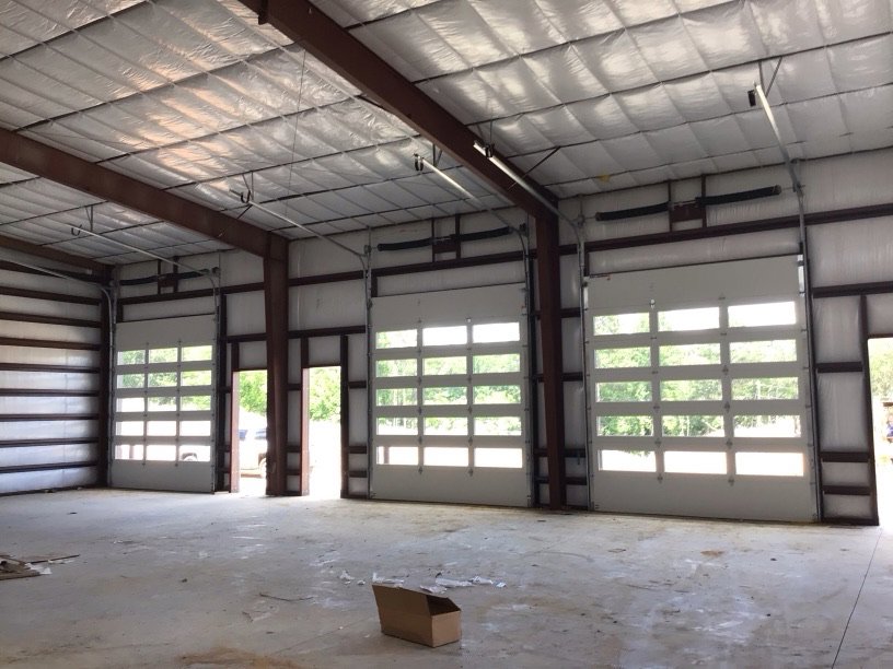 Multiple white glass-paneled commercial garage doors installed in a large building by Magic City Door in Birmingham, AL.