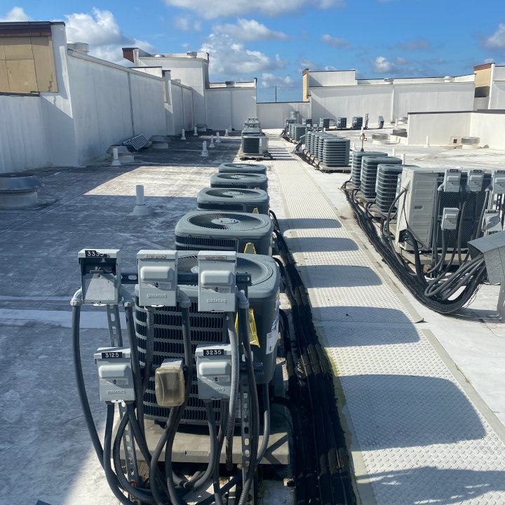 A long row of multiple outdoor commercial HVAC condenser units installed on a large rooftop, maintained by Eleven Heating and Cooling in Birmingham, AL.