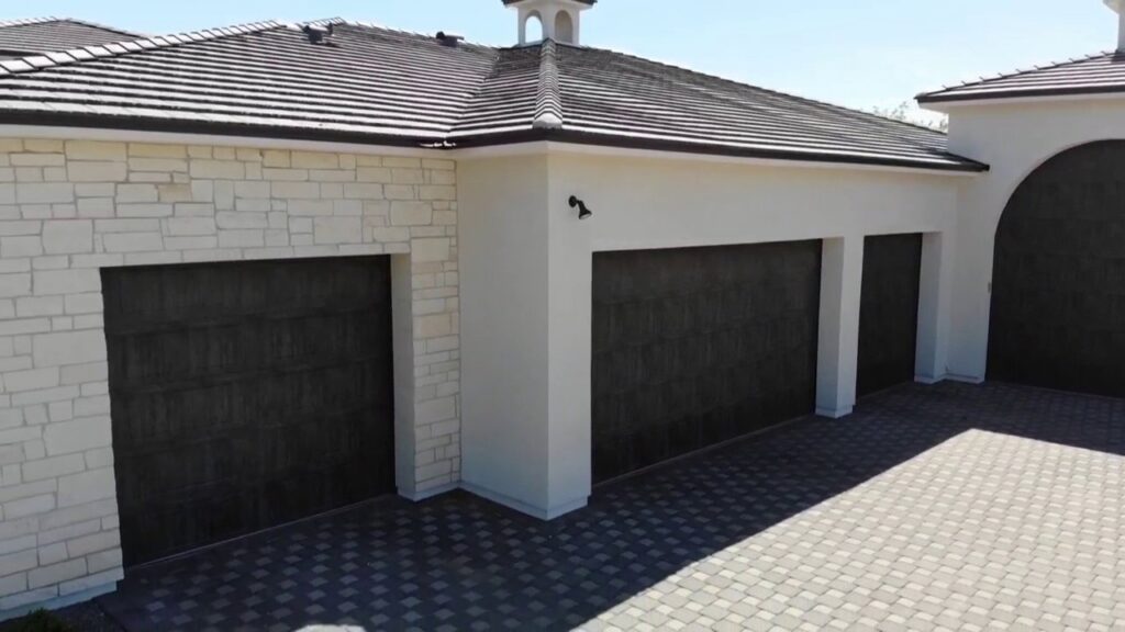 Multiple dark brown garage doors installed on a large home by Stapley Action Garage Door in Mesa, AZ.