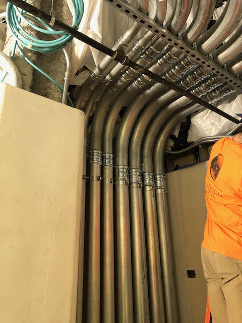 Multiple electrical conduits installed vertically along a wall by RD Graham Electric, LLC in Greensboro, NC.
