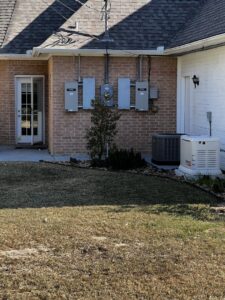 A Generac generator connected to multiple electrical panels on a brick house by Gen Central Power Systems in Houston, TX