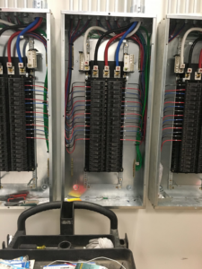 Multiple electrical panels with organized wiring and tools during an installation by GJ Electric in Salina, KS.