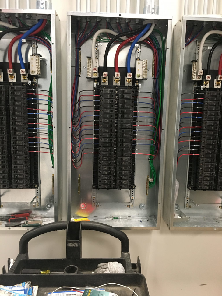 Multiple electrical panels with organized wiring and tools during an installation by GJ Electric in Salina, KS.