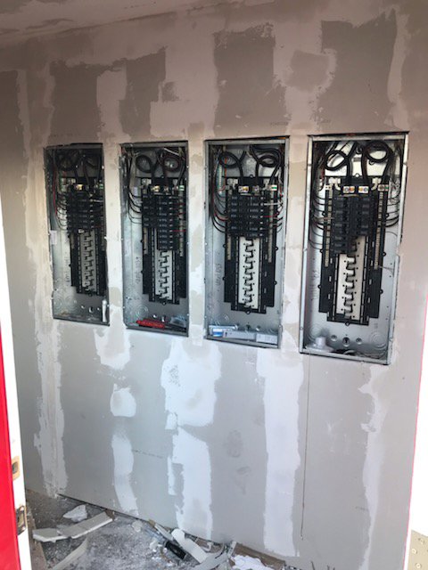 Multiple electrical panels installed in a wall during construction, showing wiring by Johnson Power and Air in Gilbert, AZ.