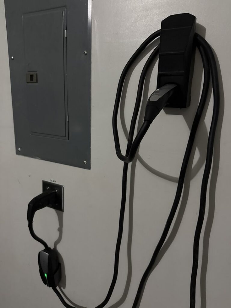 Multiple EV chargers installed next to an electrical panel, including a Tesla Wall Connector, by Davis Electric in Cleveland, OH.