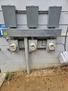 Multiple exterior electrical meters and service boxes installed on a building by Tim Lambert Electric in Fayetteville, NC.