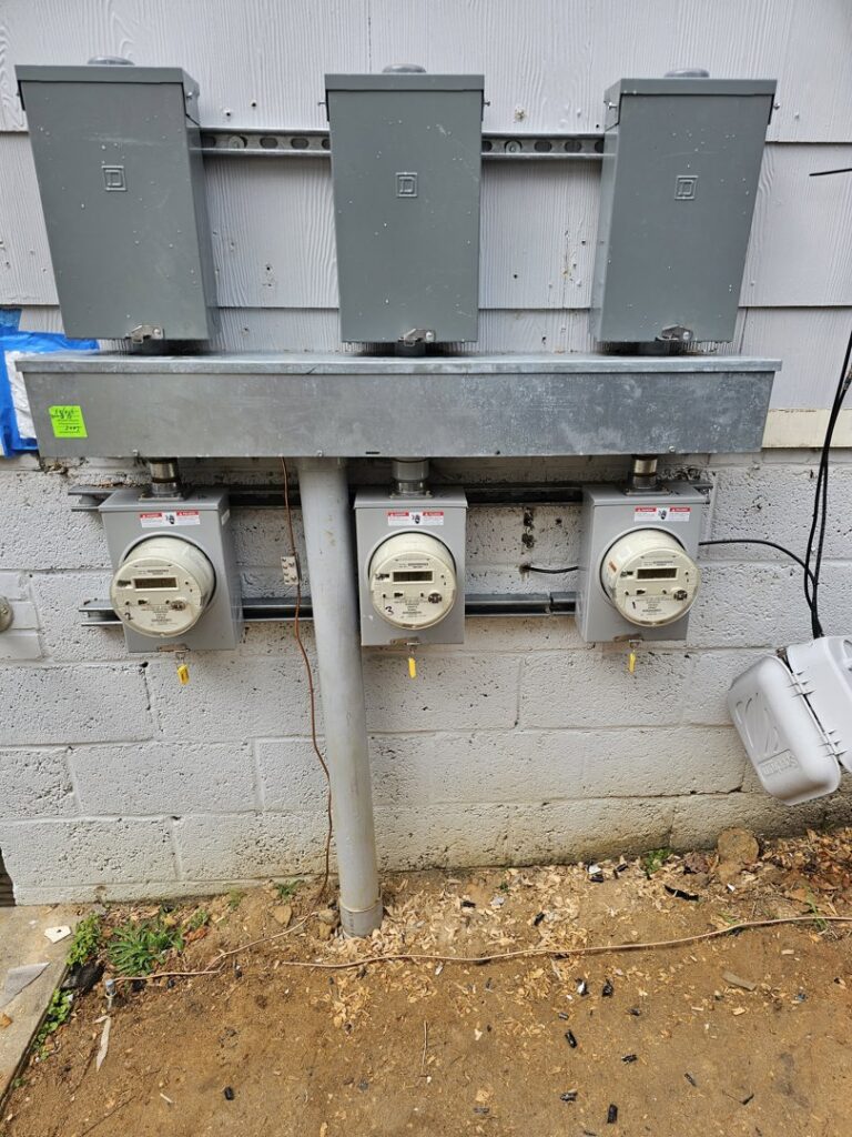 Multiple exterior electrical meters and service boxes installed on a building by Tim Lambert Electric in Fayetteville, NC.