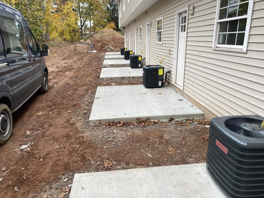 Multiple Goodman AC condenser units installed along the side of a building by Foremost Mechanical Services in Hartford, CT.