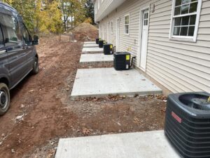 Multiple Goodman AC condenser units installed along the side of a building by Foremost Mechanical Services in Hartford, CT.