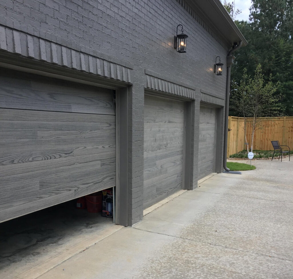 Three modern gray garage doors, with one partially open, installed by The Birmingham Man Garage Doors in Birmingham, AL.