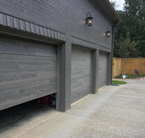 Three modern gray garage doors, with one partially open, installed by The Birmingham Man Garage Doors in Birmingham, AL.
