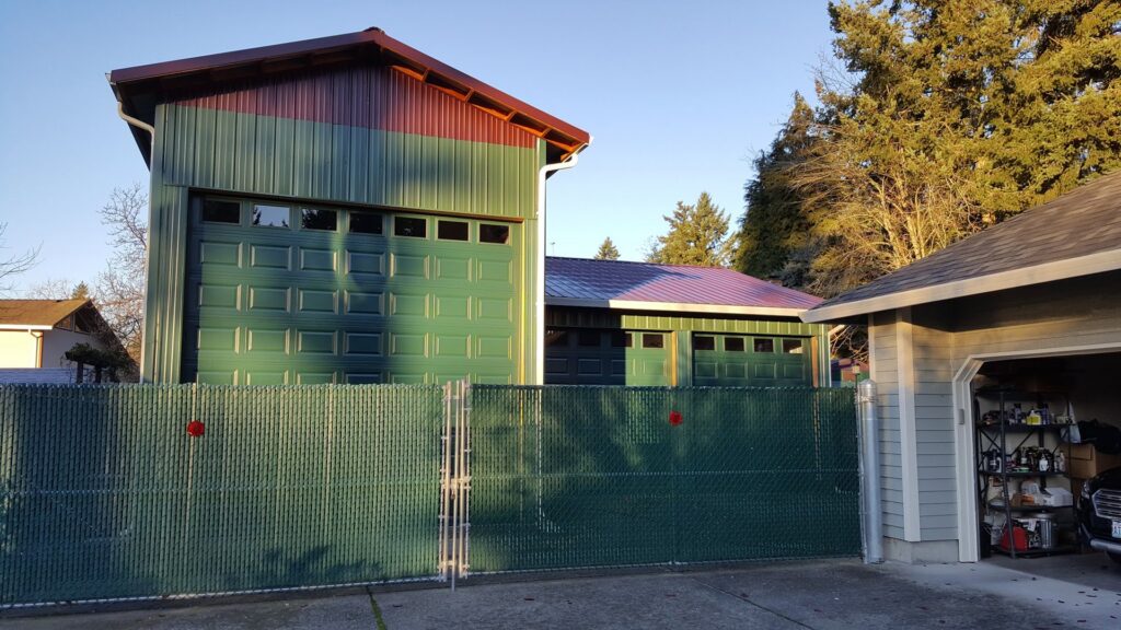 Multiple green sectional garage doors with windows on a metal building, installed by Babcock Garage Doors in Vancouver, WA