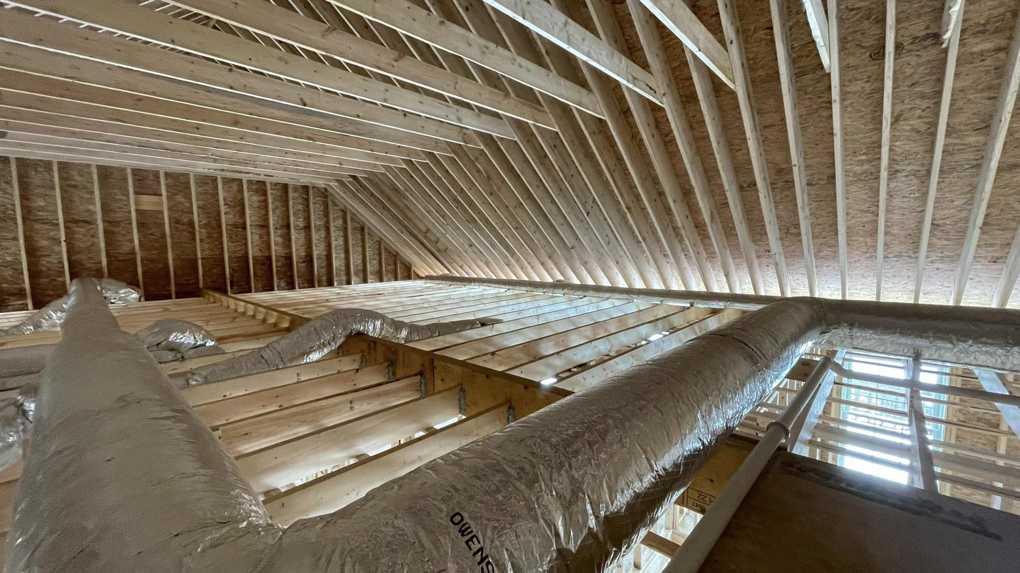 Multiple HVAC duct runs installed in an unfinished building structure by Paul Mechanical LLC in Merrimack, NH