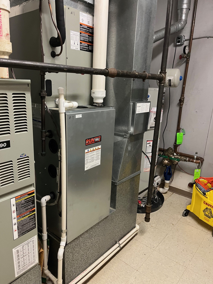 Multiple HVAC units and extensive ductwork in a utility room, showcasing work by Tri County Heating and Cooling in Longmont, CO.