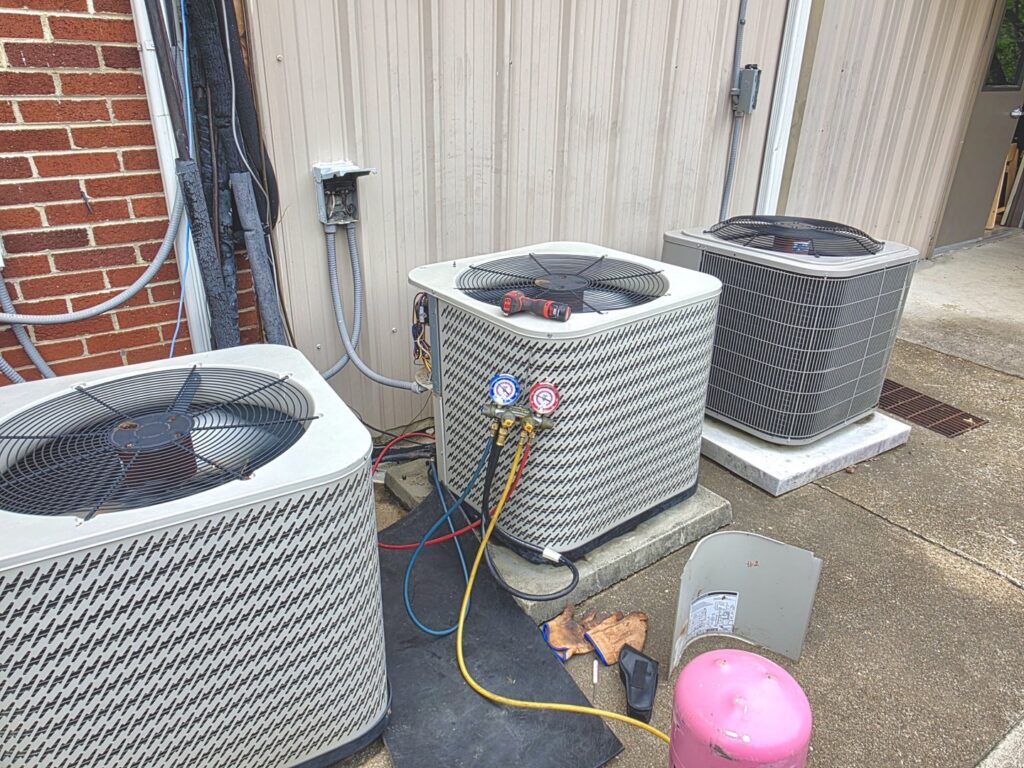Multiple outdoor HVAC units, one connected to service gauges, by Bruce Heating & Air in Kennewick, WA.