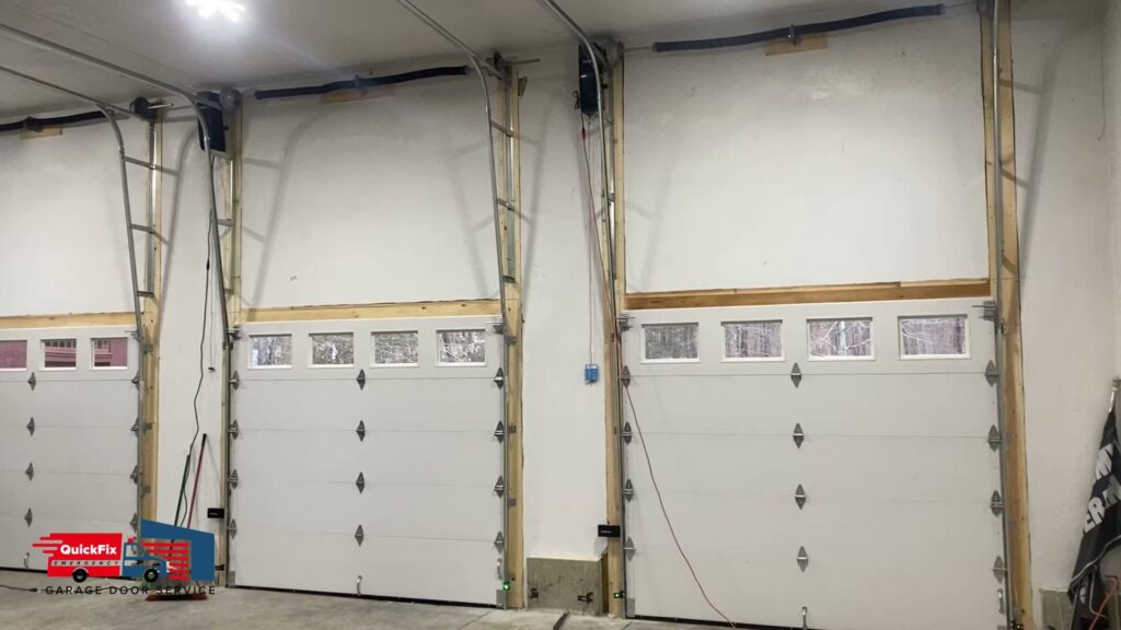 Interior view of a garage showcasing multiple newly installed white garage doors with windows by QuickFix Garage Door Service in Brighton, MA.