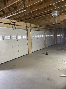 Interior view of a new construction garage with multiple white garage doors recently installed by Garage Door Repair Company, LLC in Pueblo, CO.