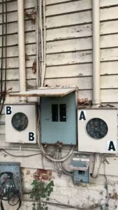 Multiple old electrical meters and panels on an exterior wall, showing potential upgrade needs by Mister Sparky of Greensboro in Greensboro, NC.