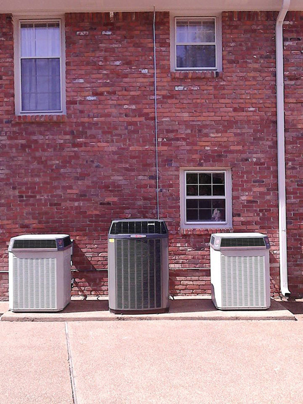 Multiple outdoor AC condenser units installed next to a brick building by C&K Air and Heating, Inc. in Olive Branch, MS.