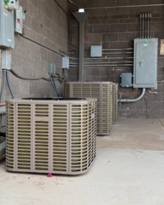 Multiple outdoor AC condenser units installed against a brick wall by Otto's Air Conditioning & Heating in Mesa, AZ.