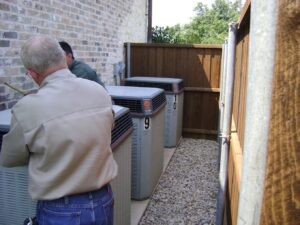 Multiple outdoor AC units being installed or serviced by technicians from Chapman Air and Heat in Dallas, TX