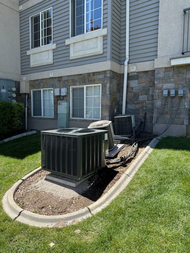 Multiple outdoor air conditioning units installed next to a building by Cutting Edge HVAC LLC in Orem, UT.