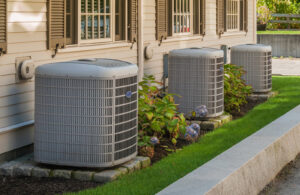 Three outdoor air conditioning units installed along the side of a house by TriForce HVAC in Layton, UT