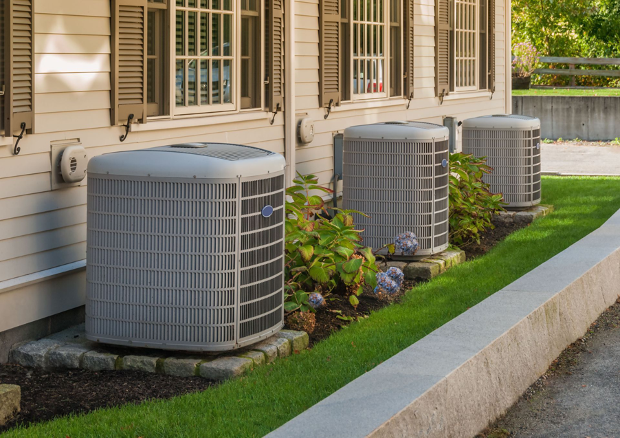 Three outdoor air conditioning units installed along the side of a residential building by McTeer's Heating & Cooling in Salisbury, MD.