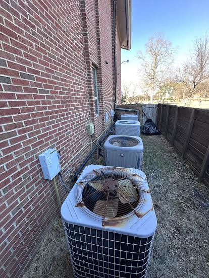 Multiple outdoor air conditioning units installed along a brick wall by Oakes AC Services, LLC in Louisburg, NC