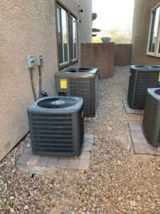 Multiple outdoor air conditioning units installed along a building by The Heating & Cooling Company LLC in Las Vegas, NV.