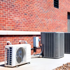 Multiple outdoor HVAC condenser units installed next to a brick building by M Heating & Cooling, Inc. in Green Bay, WI