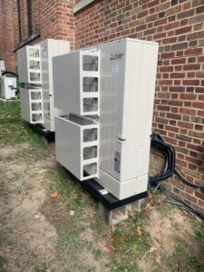 Multiple outdoor mini-split condenser units installed along a brick wall by Air Energy Solutions in North Chesterfield, VA