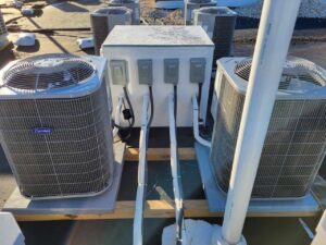 Multiple Carrier outdoor air conditioning units installed on a commercial rooftop, connected to a central power box by SANKS Mechanical in Philadelphia, PA.