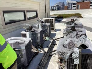 Multiple rooftop air conditioning units undergoing service or repair by Service Champions Heating & Cooling in Aurora, IL.
