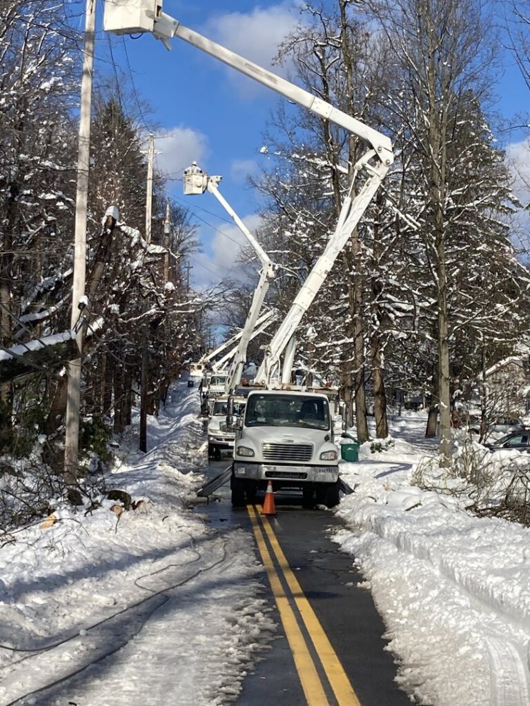 Multiple BESCO utility trucks lined up for power line repair or maintenance on a snowy road in Knoxville, TN.