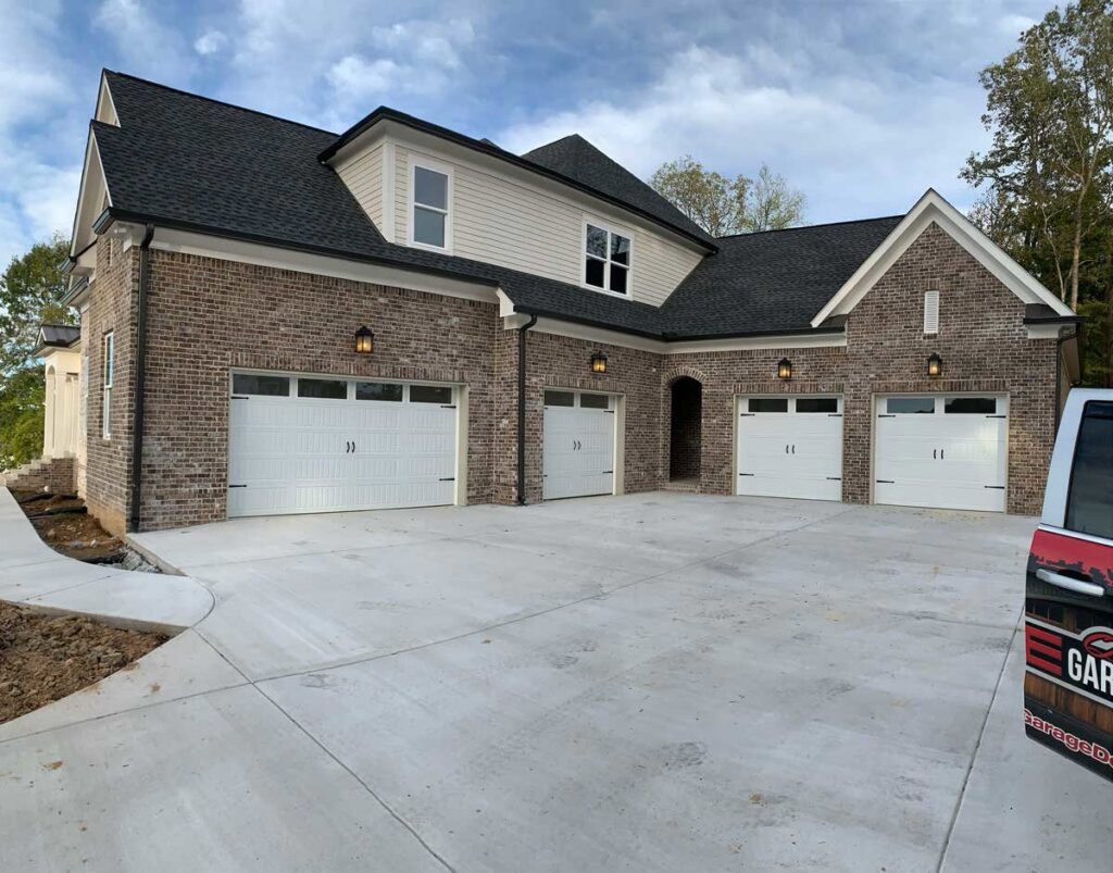 Multiple white garage doors installed on a new brick house by Rose Quality Garage Doors in Murfreesboro, TN