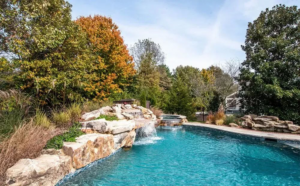 A swimming pool featuring a natural rock waterfall and lush landscaping by Top Tier Pools in Franklin, TN.