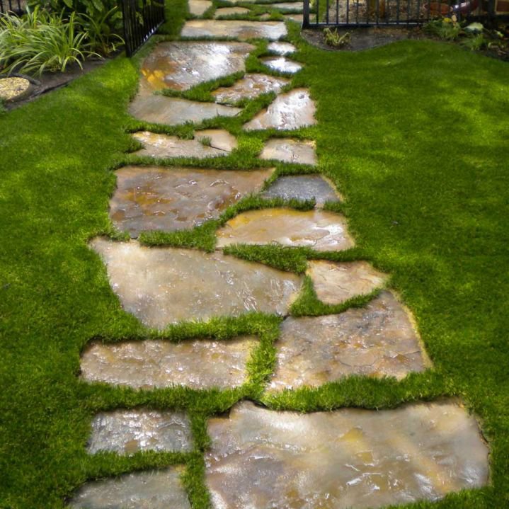 A natural stone pathway integrated into a lush green lawn, showcasing landscaping design by Miguel Landscaping LLC in Janesville, WI.