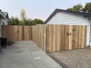 A natural wood privacy fence with two gates, creating an enclosed space next to a garage, by ZBros Fencing LLC in Boise, ID.