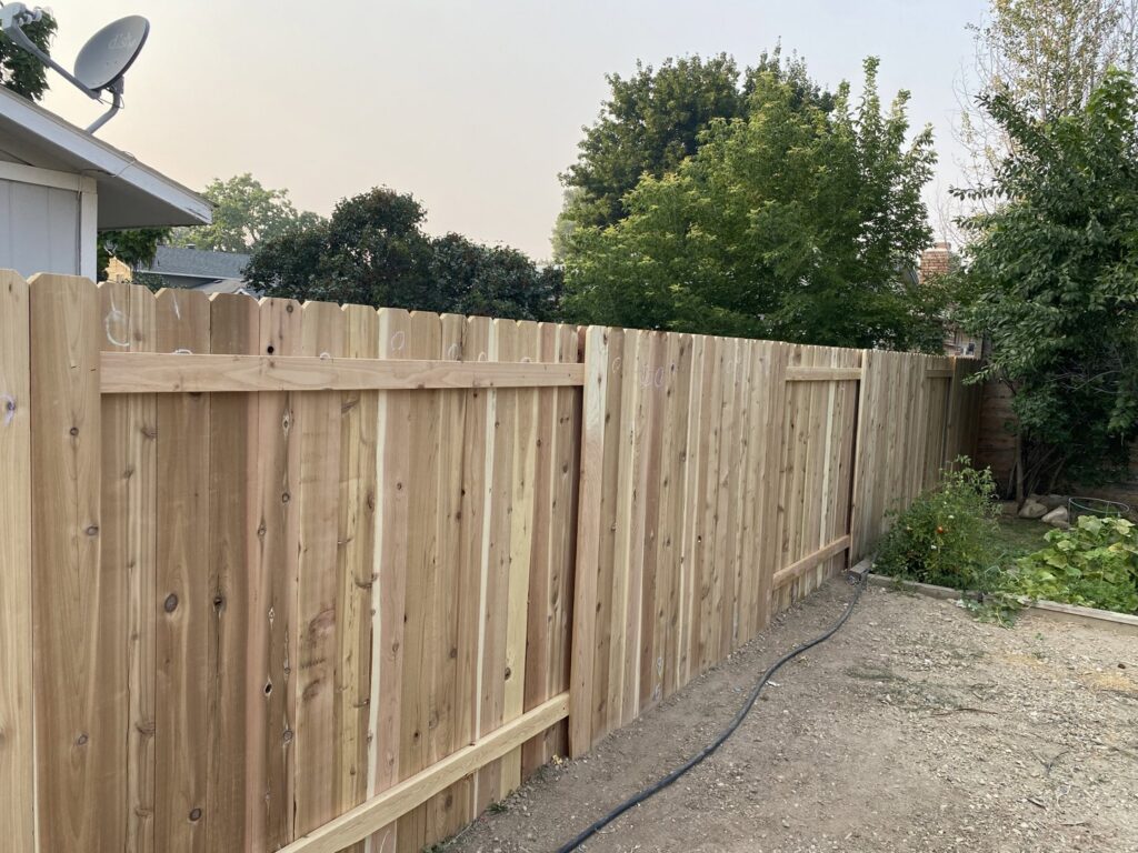 A natural wood privacy fence with a gate, enclosing a residential area, installed by ZBros Fencing LLC in Boise, ID.