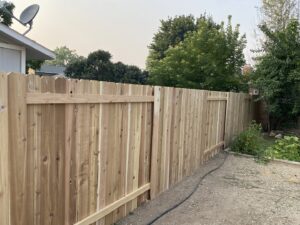 A natural wood privacy fence with a gate, enclosing a residential area, installed by ZBros Fencing LLC in Boise, ID.