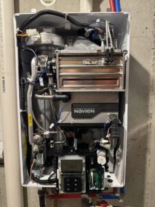 An open Navien tankless water heater showing internal components and piping by Advantage Plumbing Heating & Air in Vandalia, OH.