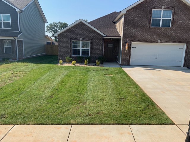 A neatly mowed and striped front lawn of a residential home by Cutting Edge Lawn Services in Islip, NY