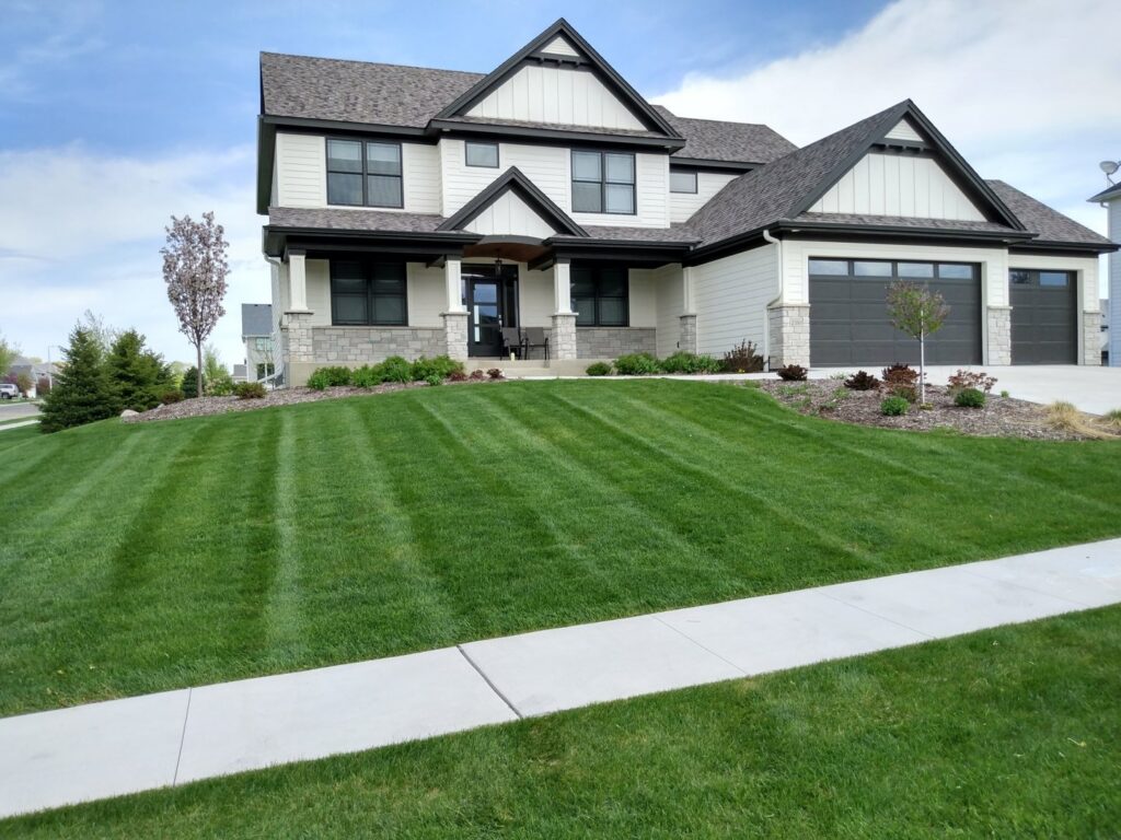 A neatly mowed front yard with clean stripes, demonstrating the quality lawn care services of Three Boys Lawncare in Rochester, MN.