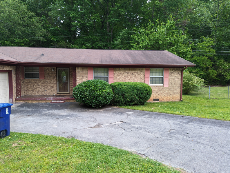 Neatly trimmed bushes in front of a brick house, showcasing shrub pruning by EGreen Lawn Pros in Chattanooga, TN.