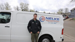 A Nelke Mechanical HVAC technician standing proudly in front of a branded service van in Keizer, OR.