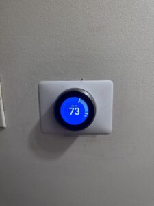 A Nest smart thermostat installed on a wall by ICare Heating & Air in Millcreek, UT.