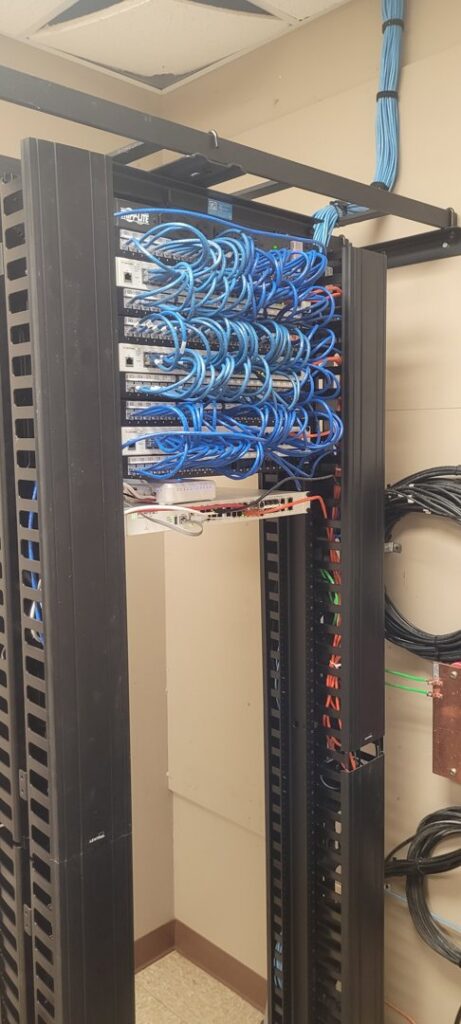Neatly organized blue ethernet cables in a server rack, installed by KS Retail Solutions in Victoria, TX
