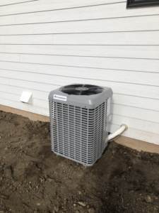 A new Champion outdoor AC unit installed next to a residential home by Air Care, an HVAC contractor in Sioux Falls, SD.